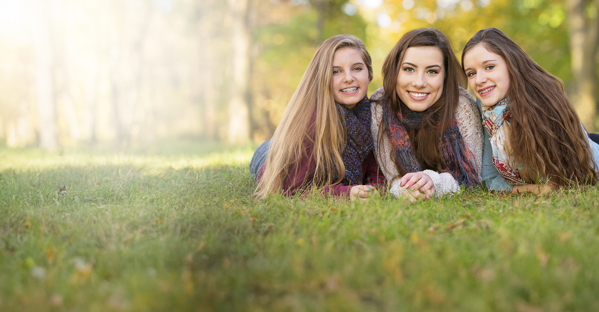 Two girls laying on grass smiling with dental orthodontics in Firestone, CO