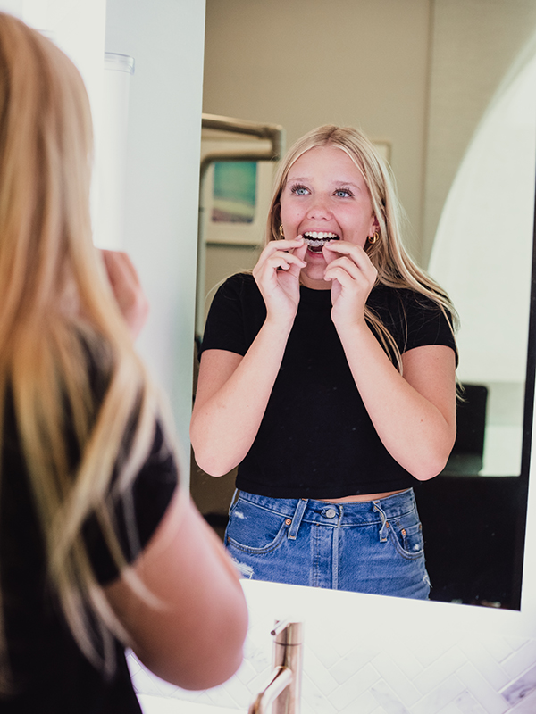 A teen in Firestone, CO placing her Invisalign clear alingers. 