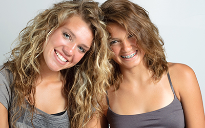 Two young girls smiling, one with braces