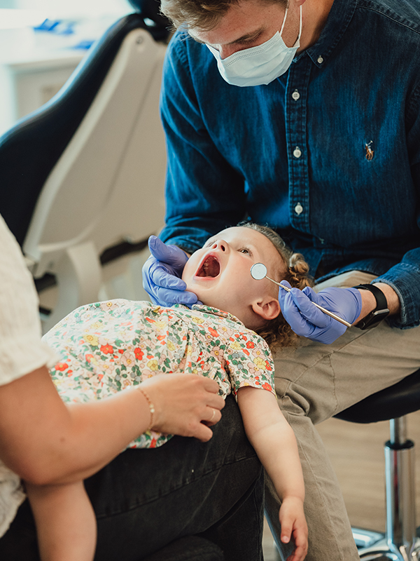 Child in parent's lap being seen by the pediatric dentist in Firestone, CO