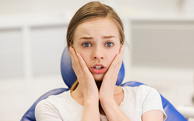 A girl sitting in a dental chair with a worried look on her face