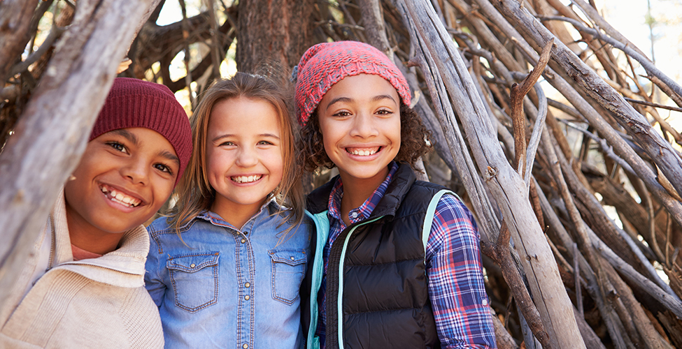Three kid outside under a wood fort
